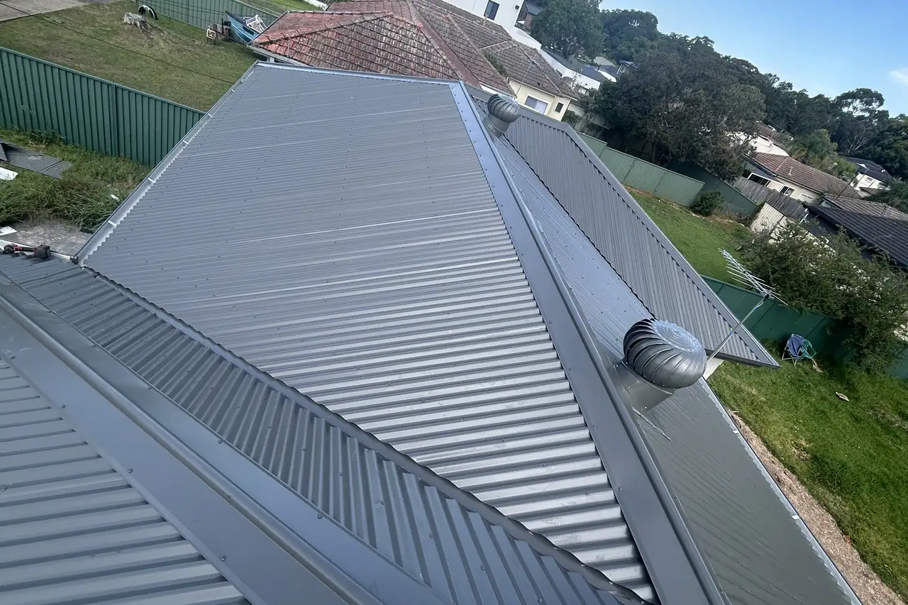 A new steel roof stepping down over a sloping backyard, a whirlybird set on the lower plane