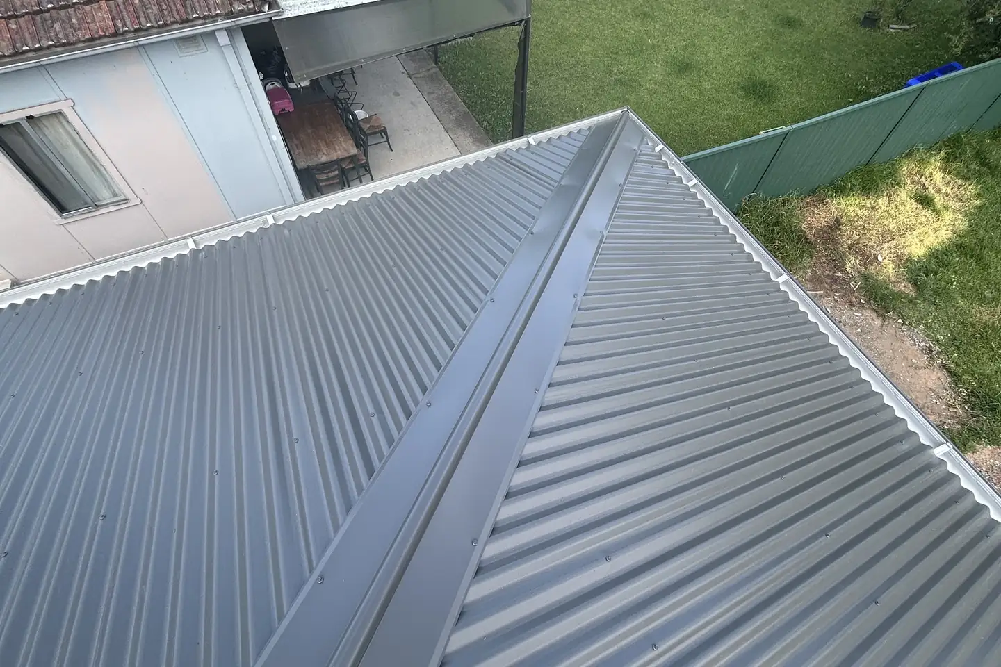 A simple new hip roof over a back garden, the fence line and lawn below
