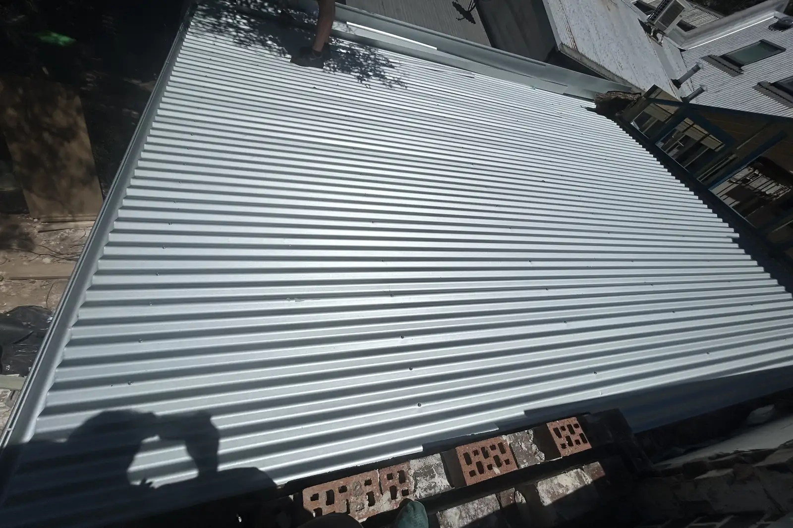 New sheeting laid over an older building, old bricks and rubble stacked on the ground below