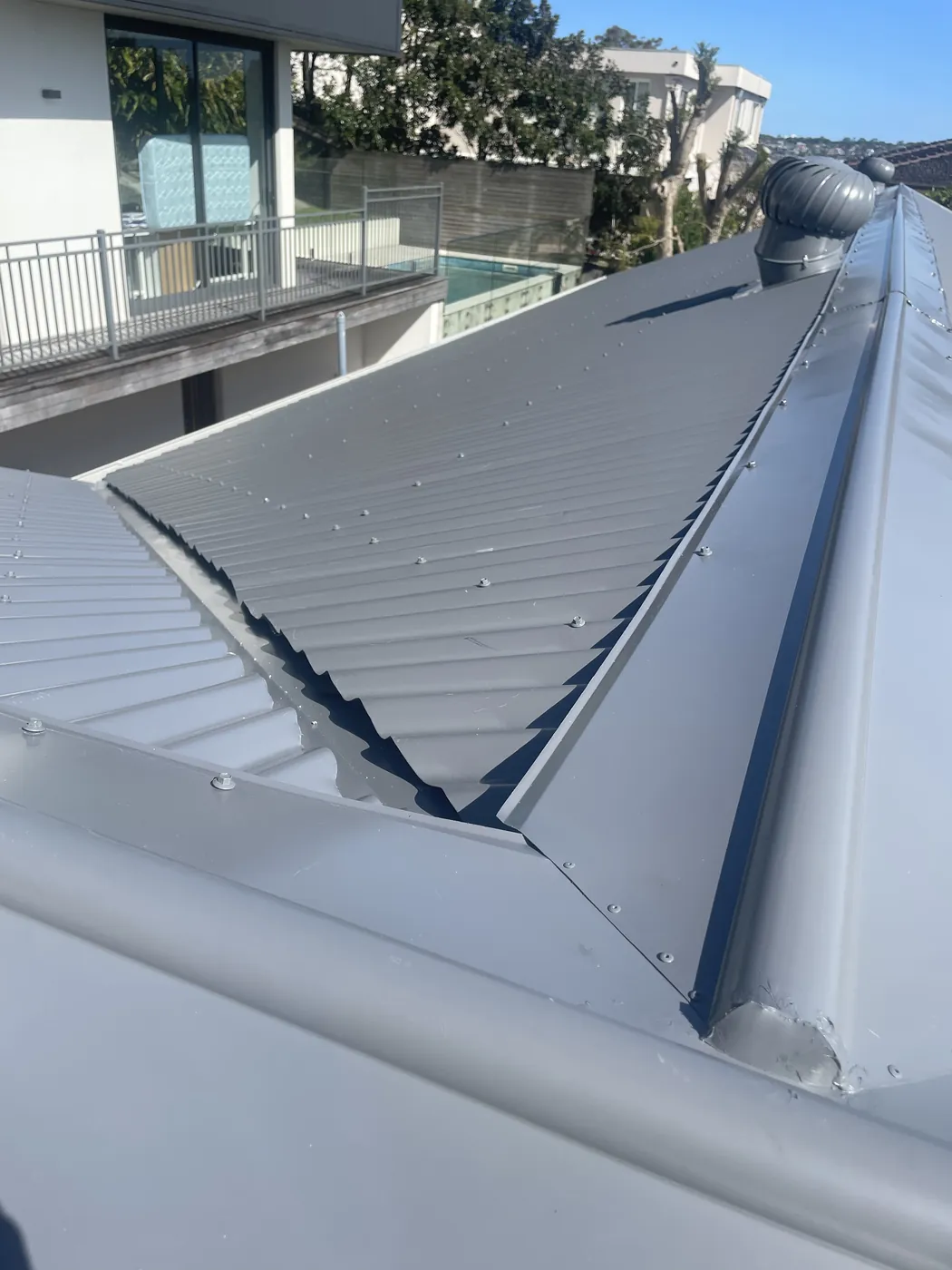 A new hip and ridge junction in pale steel, flashing folded and fixed