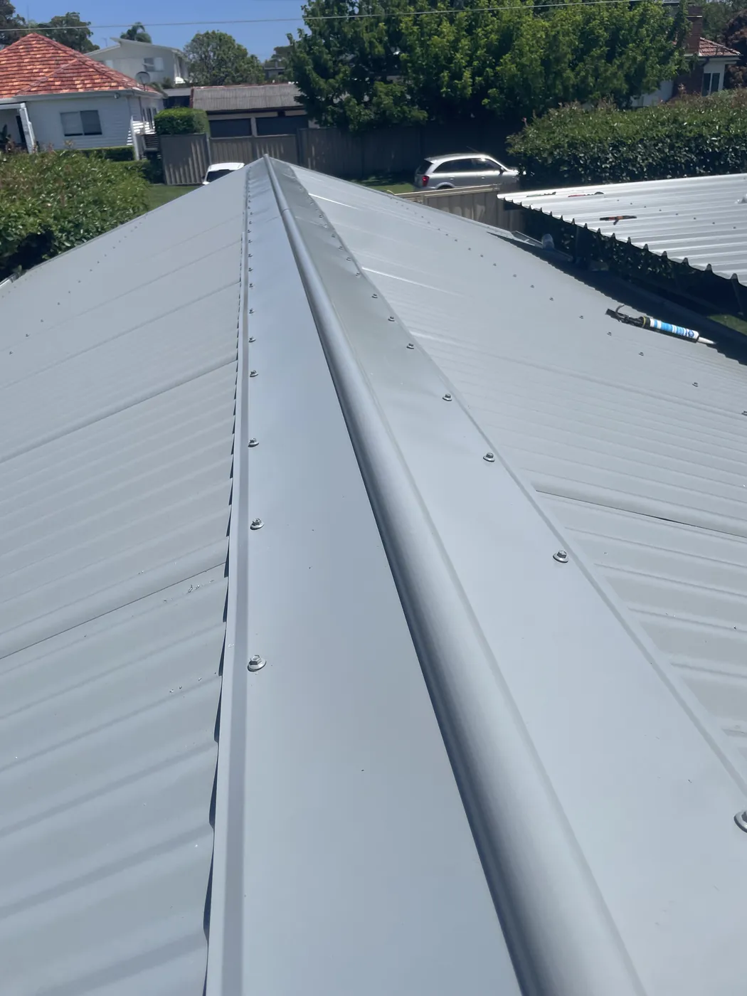 A finished ridge running the length of a house, capping fixed down and the neighbouring tiled roofs behind it