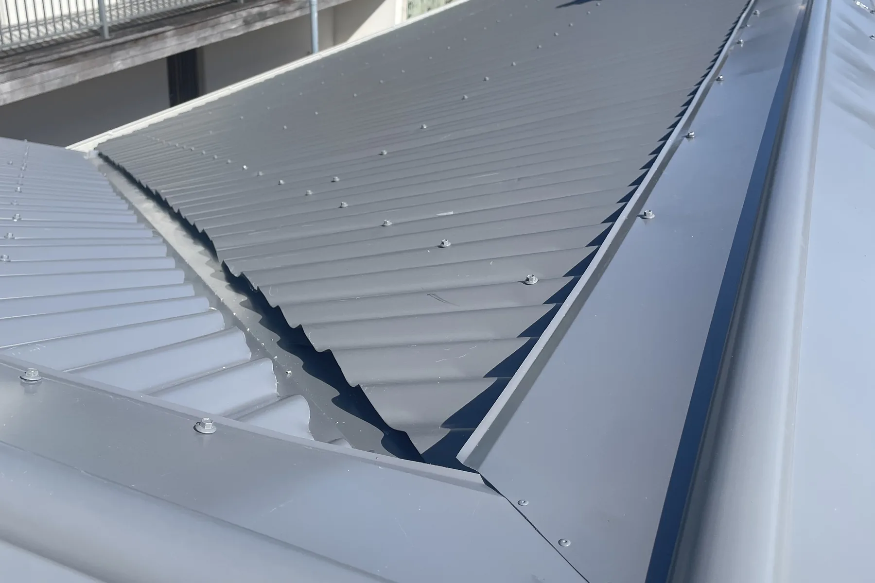 The valley where two new metal roof planes meet, the folded valley gutter and the cut sheet ends visible