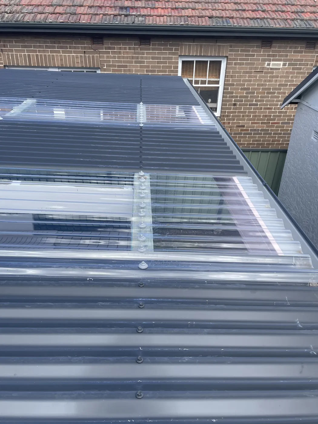 Translucent sheeting set into a run of steel over a brick wall, letting light into the space below