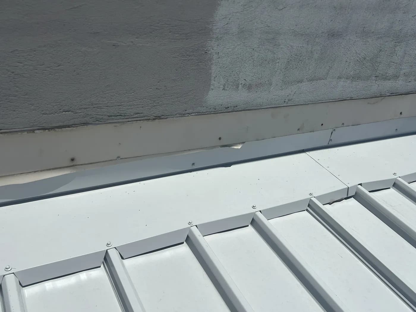 A run of flat trays finished against a rendered parapet wall, seams raised and even