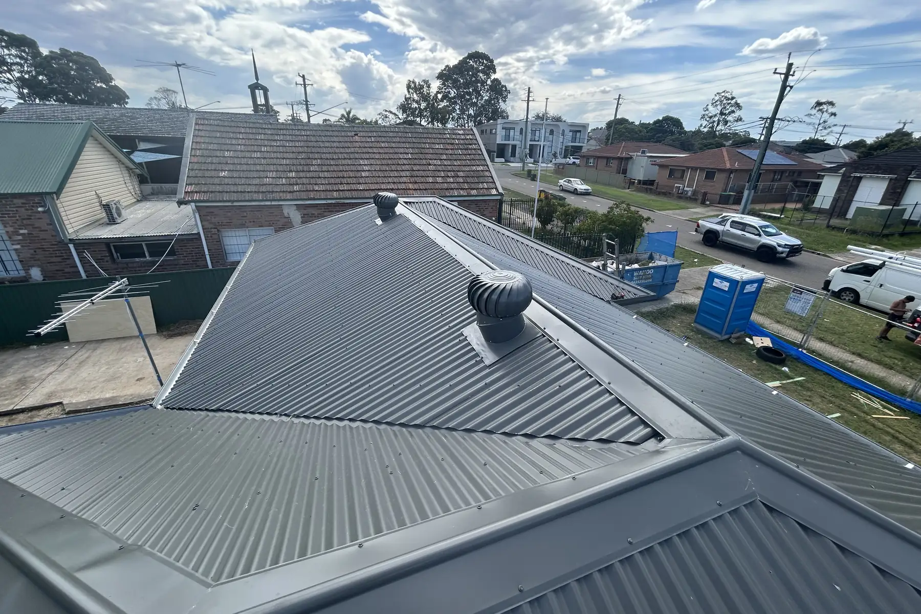 A part-sheeted hip roof looking out over a street of brick and tile houses in western Sydney